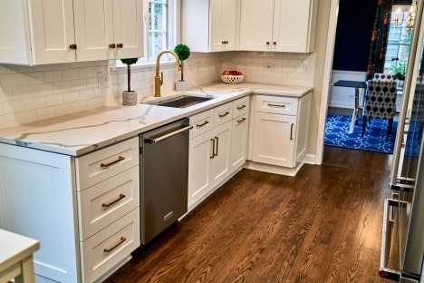 rehabbed galley kitchen with white cabinets and refinished hardwood floors