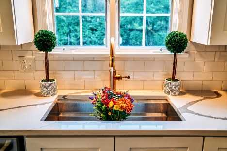 galley kitchen sink surrounded by quartz countertops and white subway tile backplash