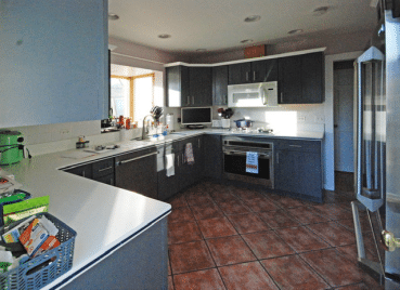 dark and dated kitchen with red tile floors and shabby blue cabinets