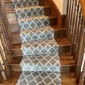 Beautiful ivory and gray stair runner on curved wood stairs.png